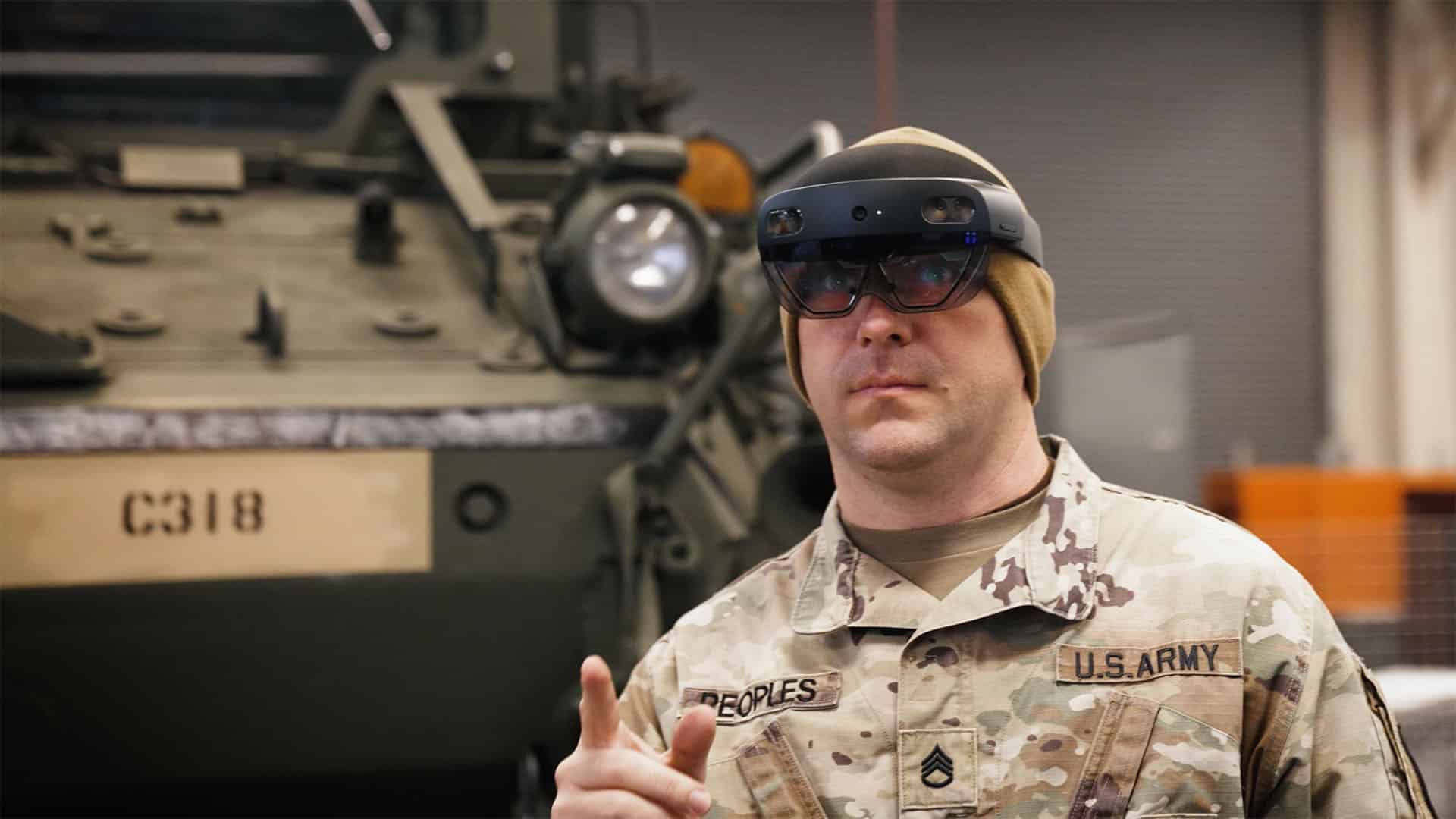 U.S. Army soldier wearing a HoloLens 2 in front of a Stryker vehicle
